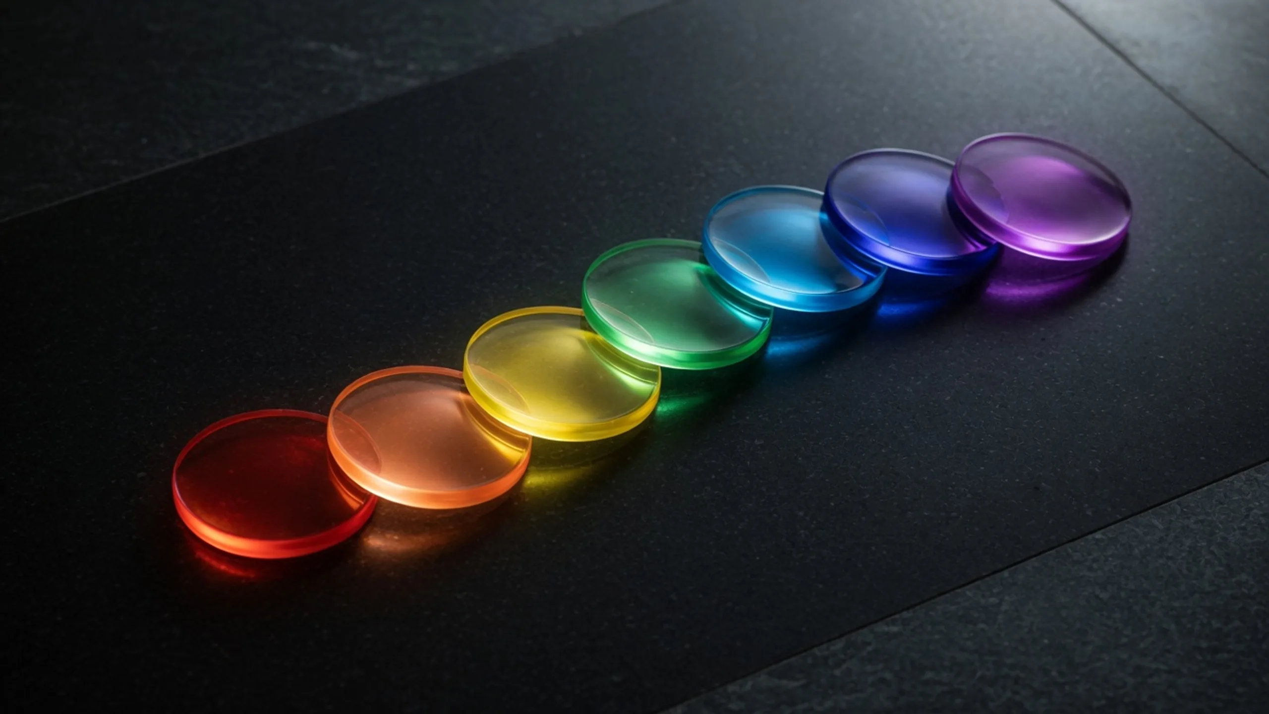 Seven luminous glass discs from red to violet arranged as a modern chakra color sequence