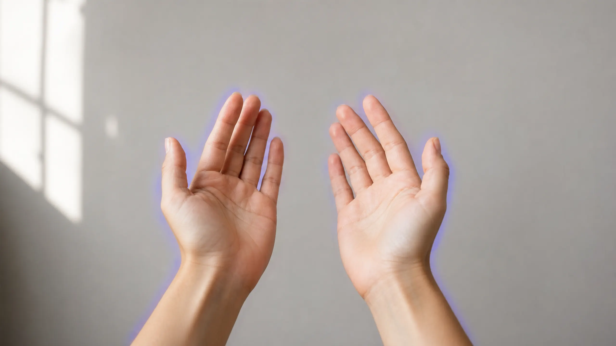 Two relaxed hands against a plain wall with a subtle blue-violet edge afterimage